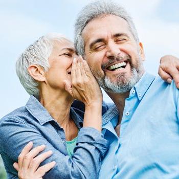 一位退休人员在她的伴侣笑的时候在他耳边开玩笑地说悄悄话.